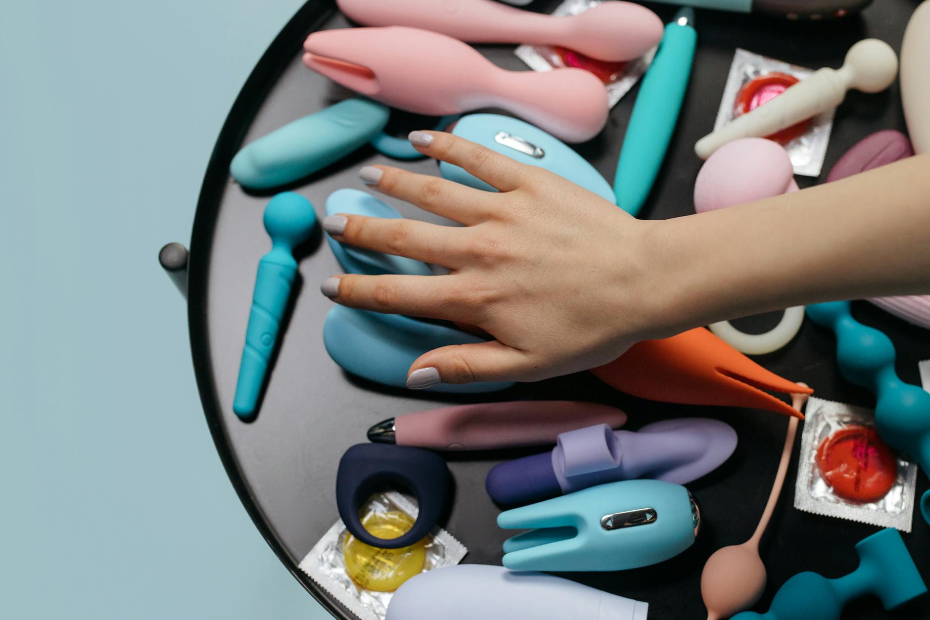 Woman holding a blue and pink vibrator, demonstrating pleasure tools for mature bodies