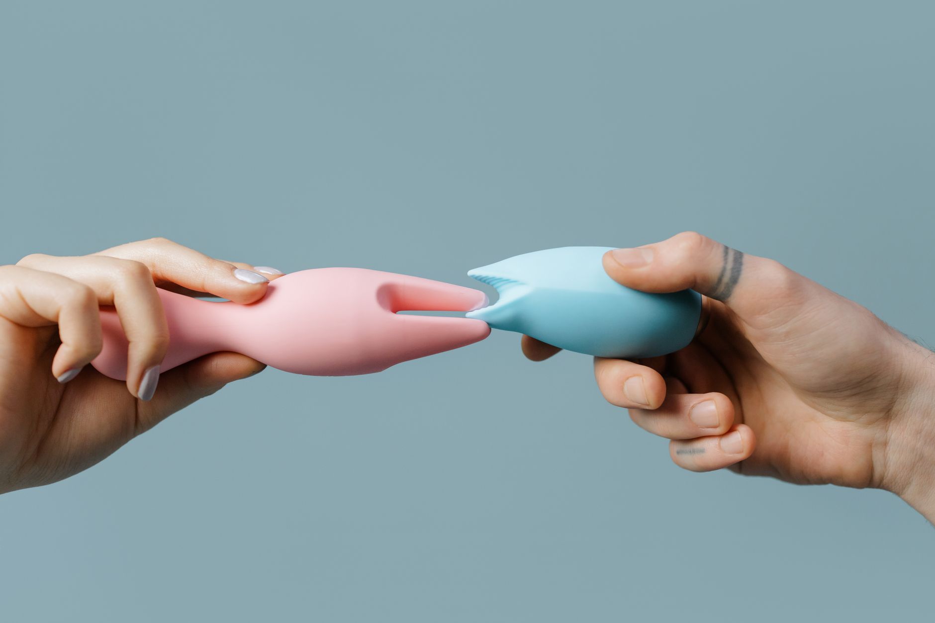 Hands holding pastel-colored silicone toys in soft light