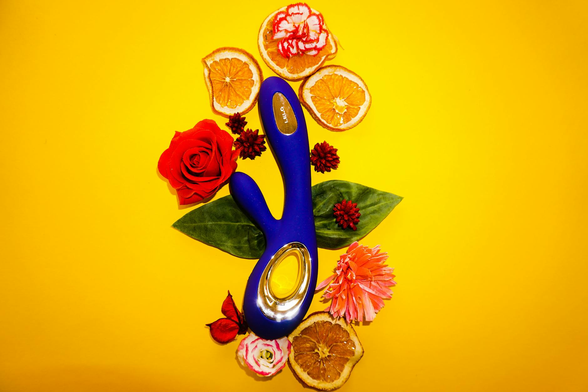 Blue lemon vibrator surrounded by flowers and citrus slices on a bright yellow background